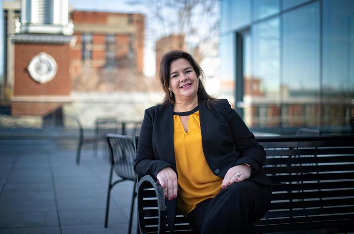 A photo of Carrie Oser outdoors on a bench. 