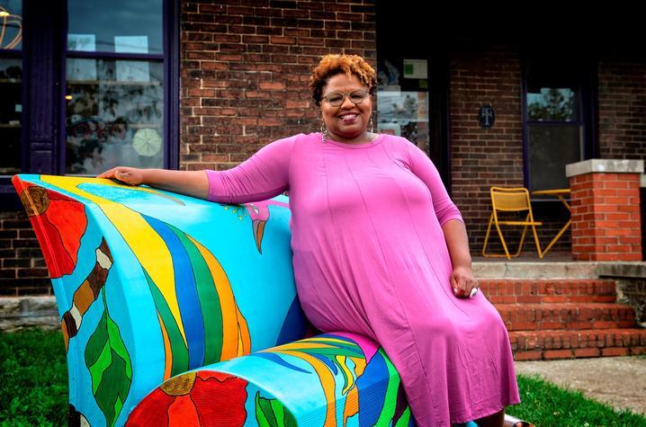 A photo of Crystal Wilkinson sitting on a couch in the front yard of a home. 